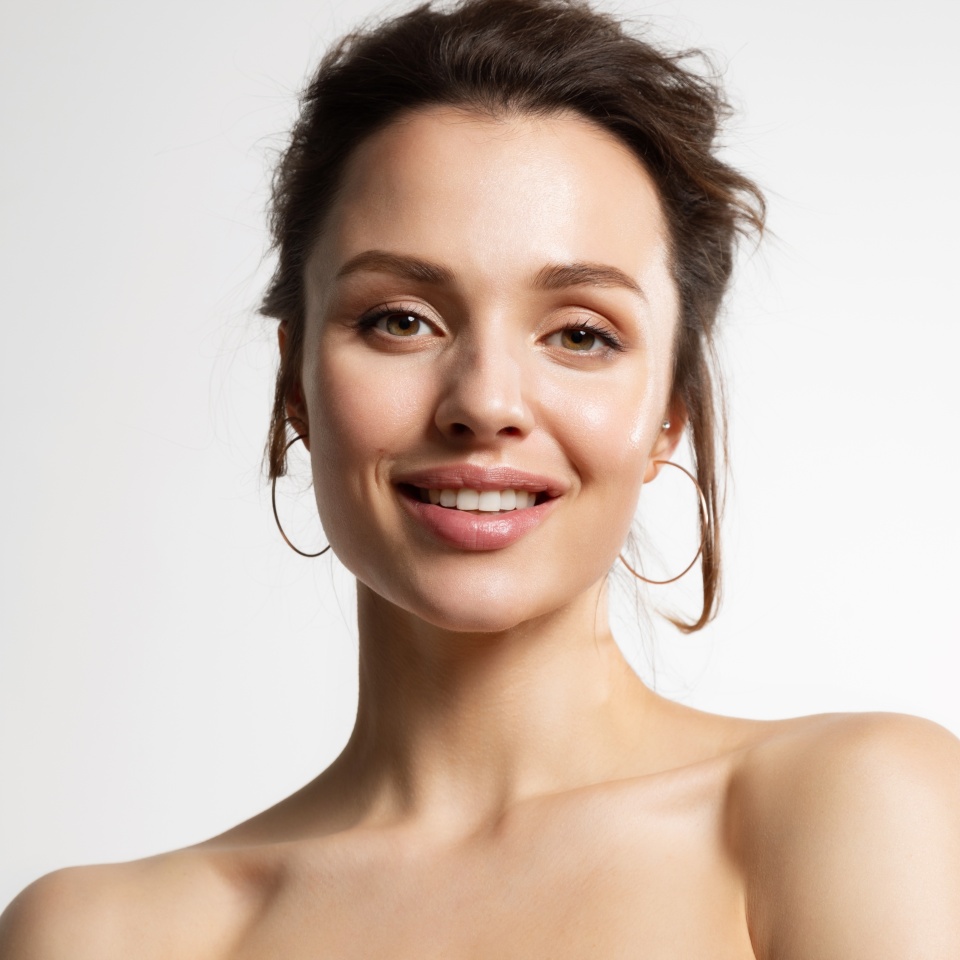Close up of young joyful woman with naked shoulders posing after cosmetic skin rejuvenation procedure. Advertising poster of natural skincare cosmetic products.