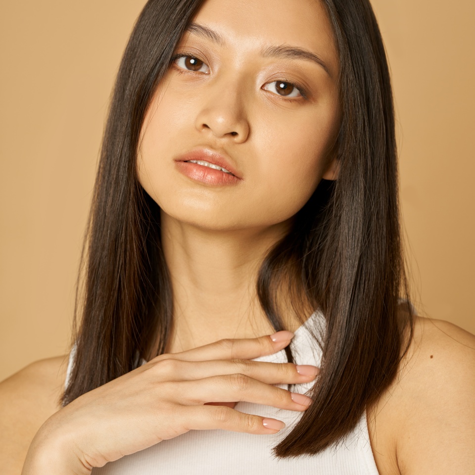 Close up portrait of stunning mixed race young woman with perfect skin looking at camera while posing isolated over light background