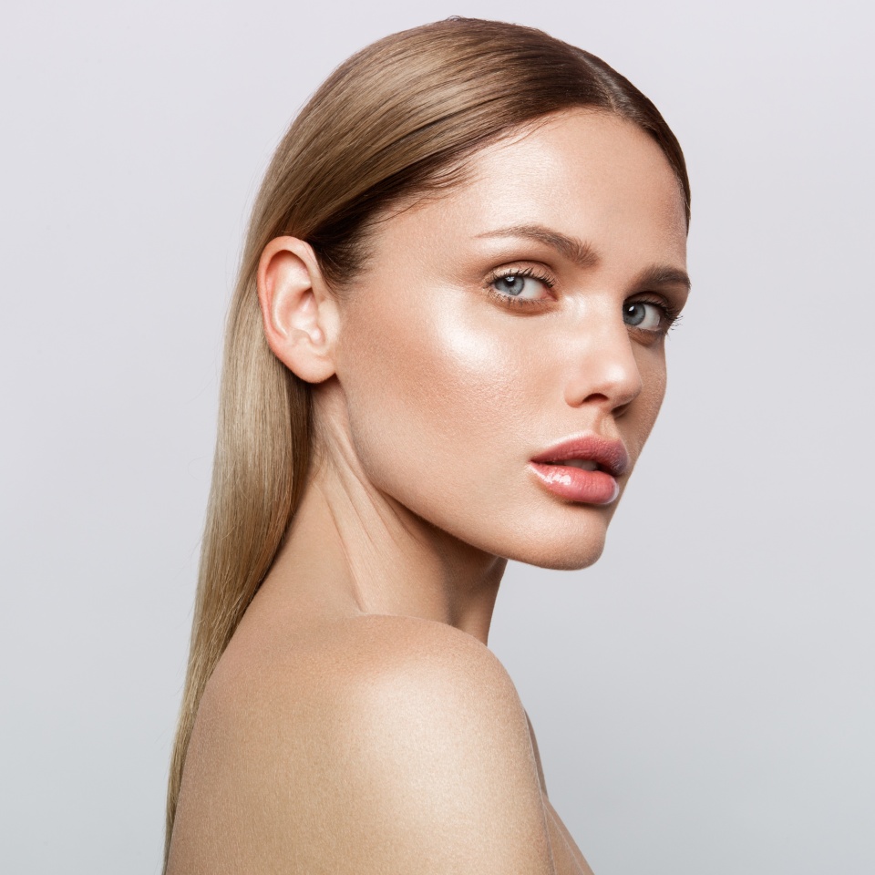 Beauty portrait of model with natural make-up. Fashion shiny highlighter on skin, sexy gloss lips make-up